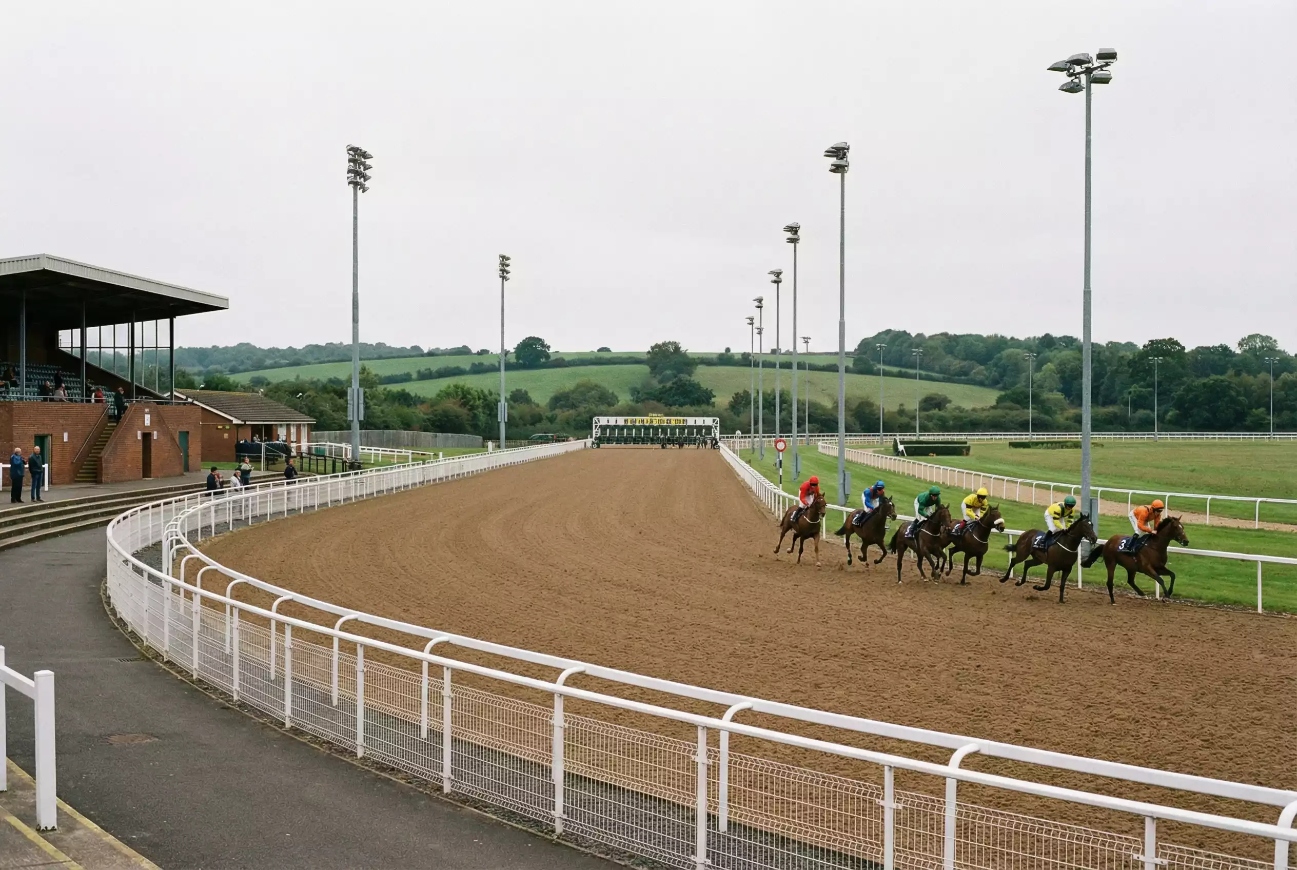 Horses racing on a synthetic all-weather surface at a British racecourse