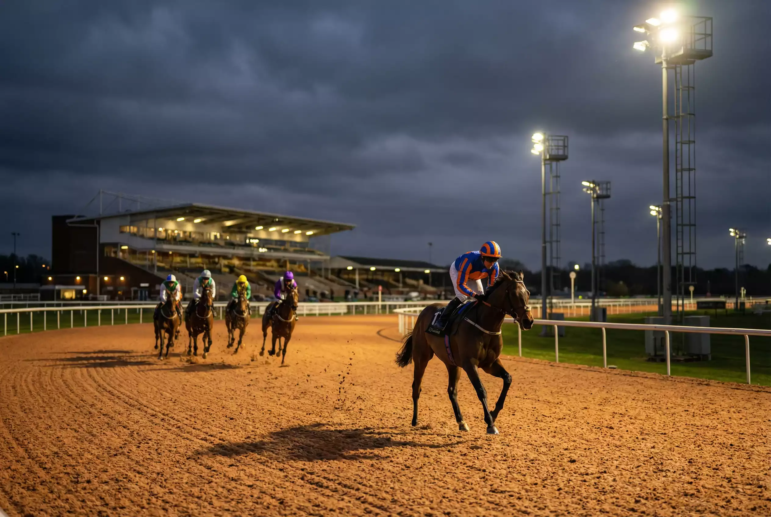 Front-running horse leading the field around a bend at Wolverhampton racecourse